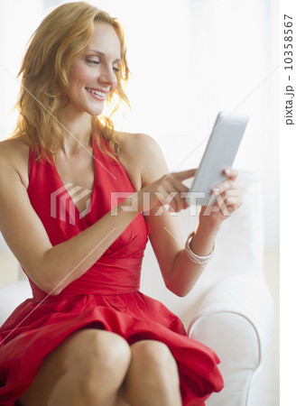 Woman in red dress using tablet pc, studio shot 10358567
