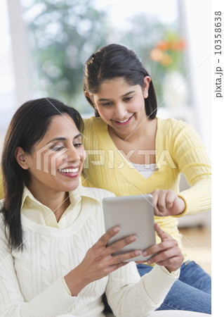 Mother and daughter (12-13) using digital tablet 10358638
