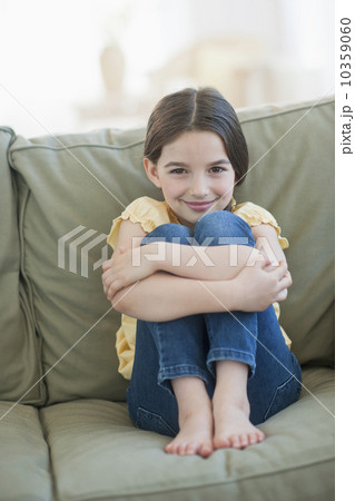Portrait of girl (8-9) sitting on sofa 10359060