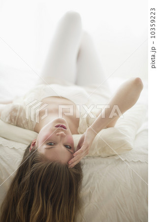 Studio portrait of young woman lying on bed 10359223