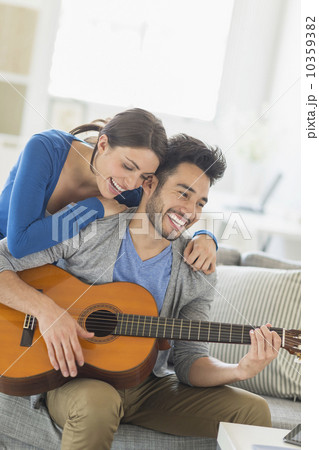 Man playing guitar while woman embracing him 10359382