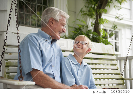 Grandfather and grandson (10-11) sitting on porch swing 10359510