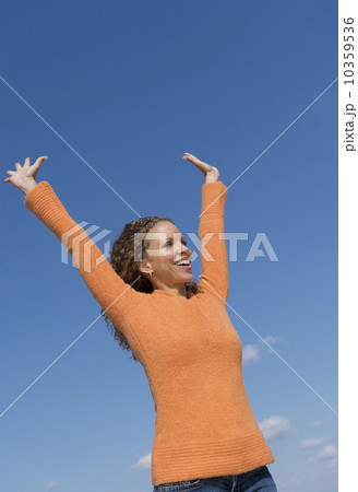 Mature woman with arms raised towards blue sky 10359536