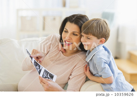 Pregnant woman with son (4-5) looking at ultrasound photo 10359626