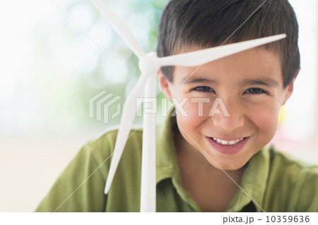 Portrait of boy (6-7) holding scale model of wind turbine 10359636