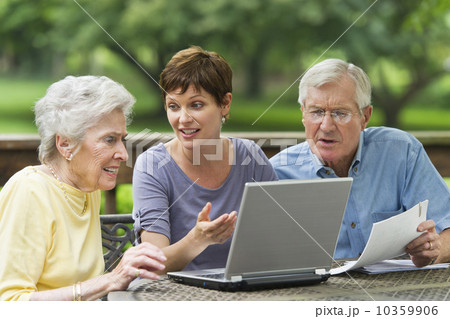 Senior parents and adult daughter using laptop on porch 10359906