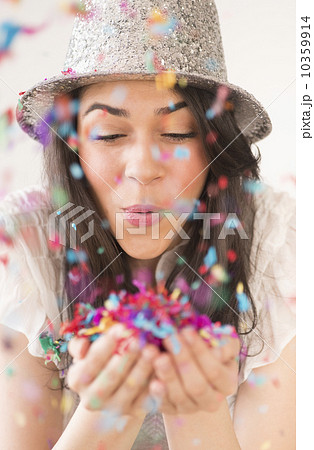 Portrait of young woman blowing confetti 10359914