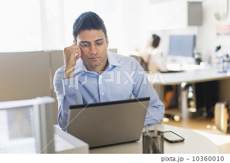 Businessman working on laptop, businesswoman in background 10360010