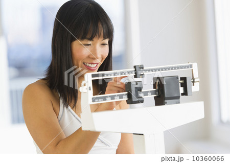 Smiling woman checking her weight Smiling woman checking her weight 10360066