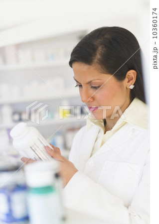 Pharmacist reading label on medicine bottle 10360174