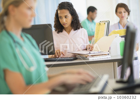 Doctors and nurses working at desks in hospital 10360232