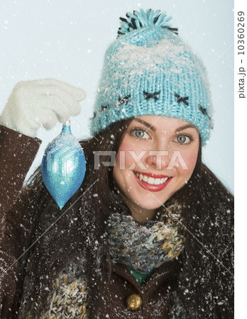 Studio portrait of woman in winter clothing holding Christmas ornament Studio portrait of woman in winter clothing holding Christmas ornament 10360269