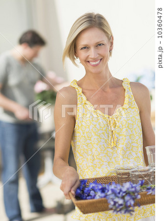 Woman carrying tray with crockery and flowers Woman carrying tray with crockery and flowers 10360478