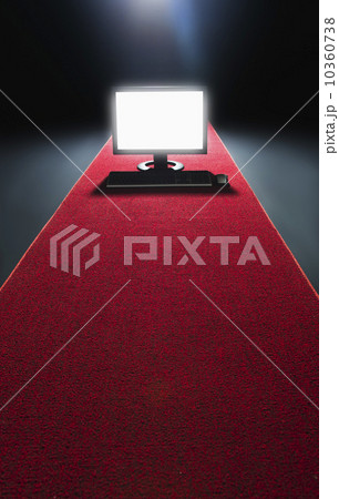Studio shot of glowing computer on red carpet 10360738