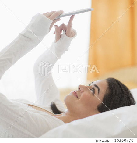 Young woman lying on bed using tablet pc 10360770