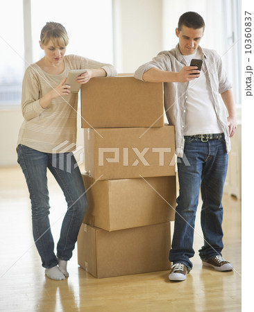 Couple leaning on cardboard boxes during relocation 10360837