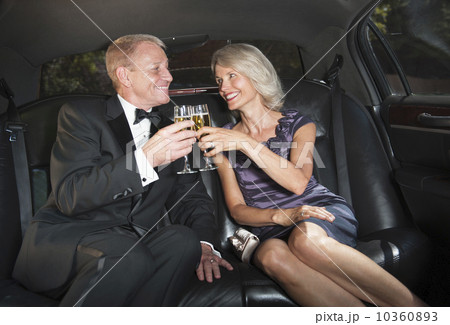 Parents of bride drinking champagne inside limousine 10360893