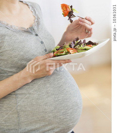 Midsection of pregnant woman eating salad Midsection of pregnant woman eating salad 10361031