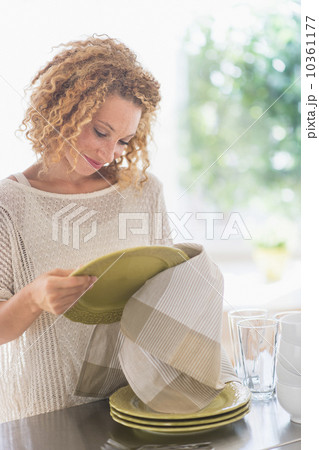 Young woman drying plates in kitchen 10361177