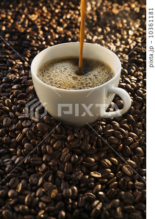 Pouring coffee into cup on coffee beans, studio shot 10361181