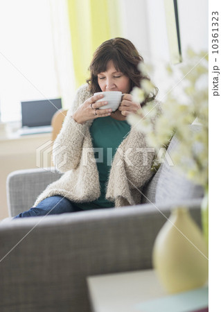 Woman sitting on sofa holding hot drink 10361323
