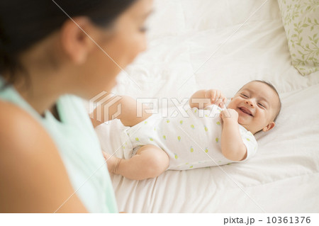 Mother looking at baby (2-5 months) lying on bed 10361376