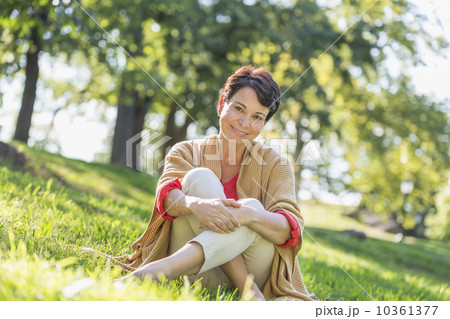 Mature woman sitting on grass in park 10361377