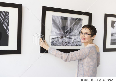 Woman hanging photographs in art gallery 10361992