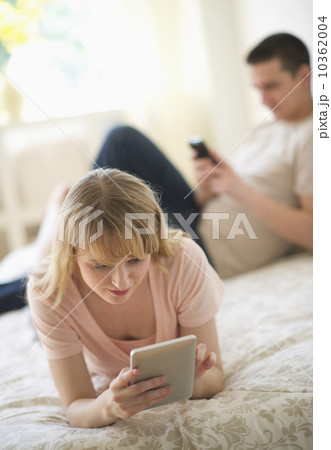 Couple lying on bed and using digital devices 10362004