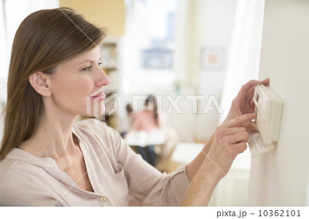 Woman adjusting house alarm Woman adjusting house alarm 10362101
