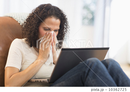 Portrait of woman sitting with laptop and blowing nose Portrait of woman sitting with laptop and blowing nose 10362725