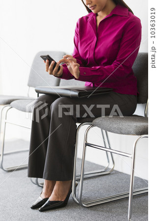 Woman sitting in waiting room and text messaging 10363019