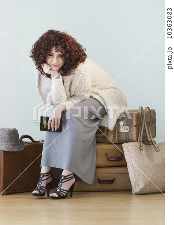 Woman sitting on stack of vintage suitcases 10363083