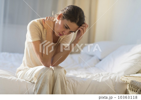 Young woman sitting on bed with headache 10363118
