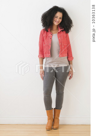 Portrait of smiling mid adult woman standing against wall 10363138