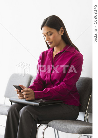 Woman sitting in waiting room and text messaging 10363345