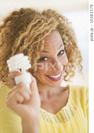 Portrait of smiling young woman holding light bulb 10363579