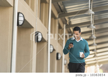 Man walking outside building and text messaging 10363654