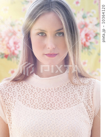 Portrait of young woman in front of floral wall paper 10364120