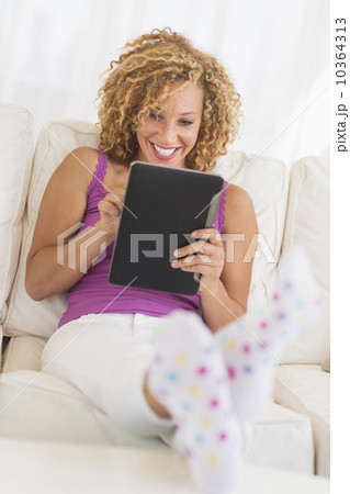 Young woman sitting on sofa with digital tablet Young woman sitting on sofa with digital tablet 10364313