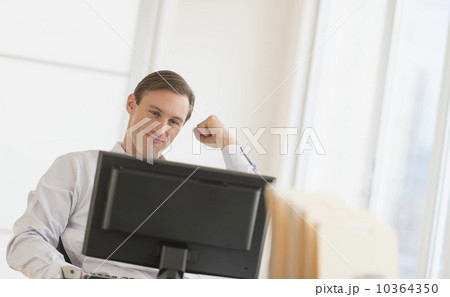 Office worker cheering in front of computer Office worker cheering in front of computer 10364350