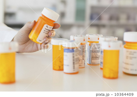 Pharmacist holding pill bottle 10364409