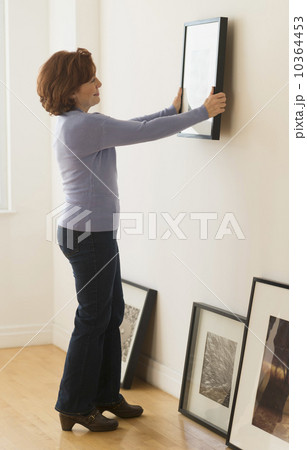 Woman hanging picture on wall Woman hanging picture on wall 10364453