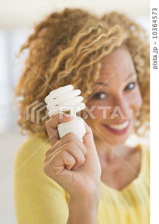 Portrait of smiling young woman holding light bulb 10364573
