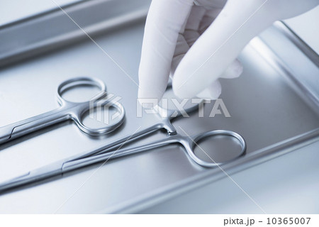 Close up of hand in surgical glove choosing dental forceps, studio shot 10365007