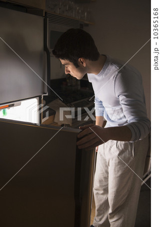 Man opening fridge at night 10365168