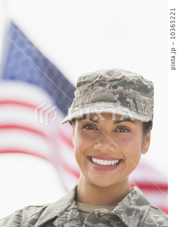 Portrait of female army soldier, American flag in background 10365221
