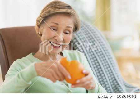 Portrait of senior woman peeling orange 10366061