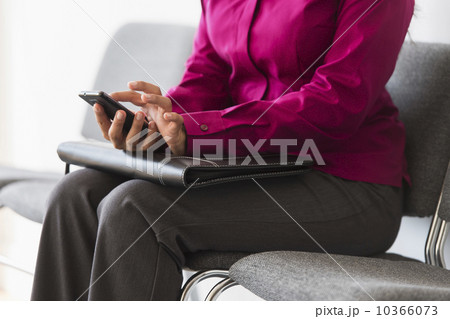 Woman sitting in waiting room and text messaging 10366073