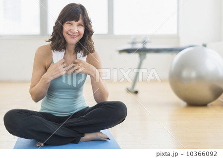 Portrait of woman sitting on mat in gym 10366092